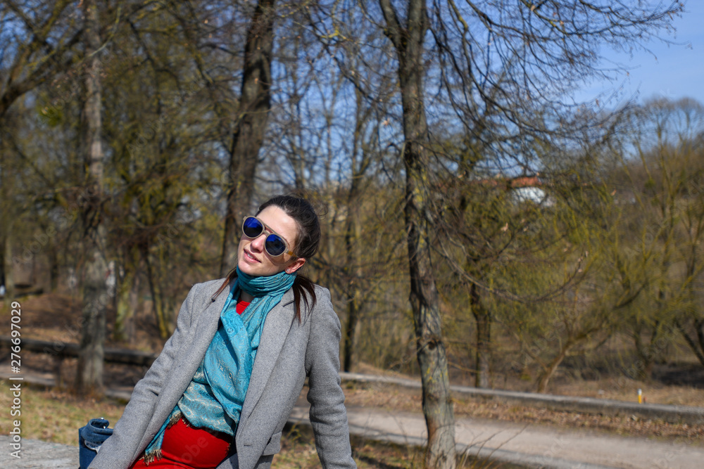 Pregnant girl in a red dress in the park. Portrait of a beautiful pregnant woman in a red dress and blue scarf, in a gray coat. Pregnant girl in a red dress in the park. Portrait of a beautiful pregnant woman in a red dress and blue scarf, in a gray coat.