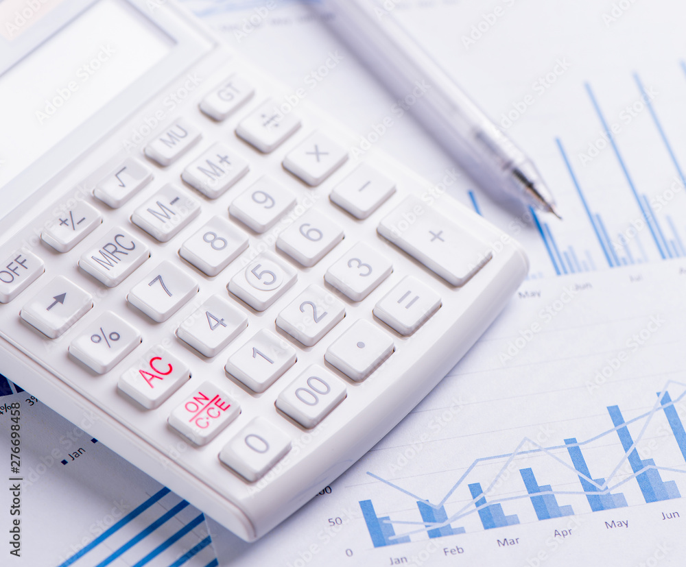White calculator and report with chart and graph, concept of annual financial profit overview, banking and investment, close up, copy space, macro White calculator and report with chart and graph, concept of annual financial profit overview, banking and investment, close up, copy space, macro