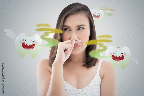 Bild auf Leinwand Asian woman in white dress catch her nose because of a bad smell against gray ba
