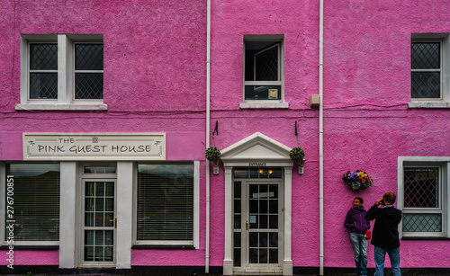 woman in front of a pink house