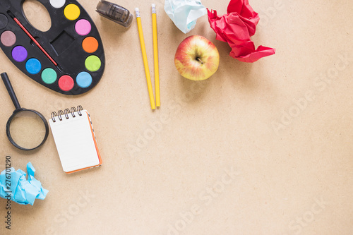 Apple and magnifying glass near stationery
