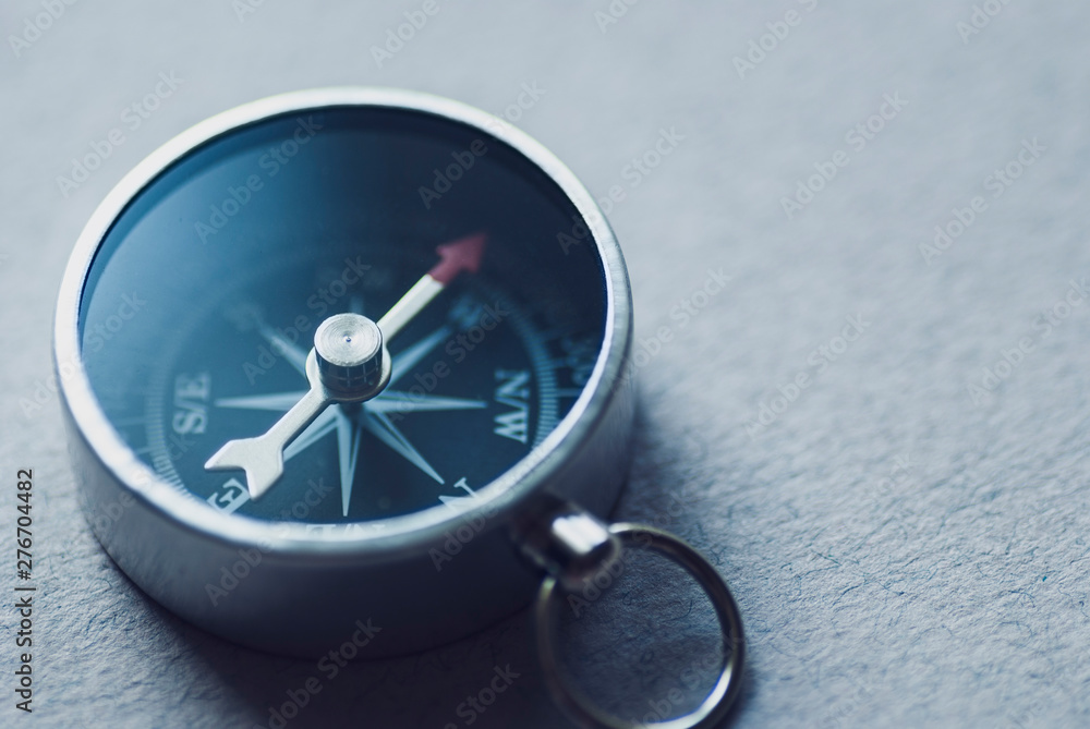 Small metallic magnetic compass on textured grey Small metallic magnetic compass on textured grey