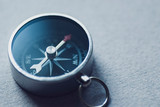 Small metallic magnetic compass on textured grey