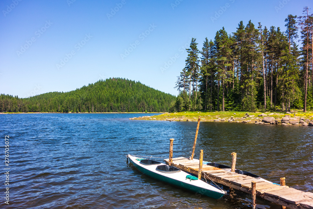 Two boats on wooden pier in mountain lake during hot summer day