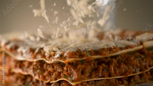 Appetizing meat lasagna is sprinkled with pieces of grated cheese. Parmesan.Very beautiful studio shot. Slow motion. Camera Phantom Flex 4K.
