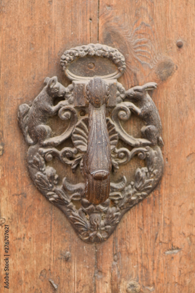 An old, weathered door knocker on an old wooden door in Spain.
