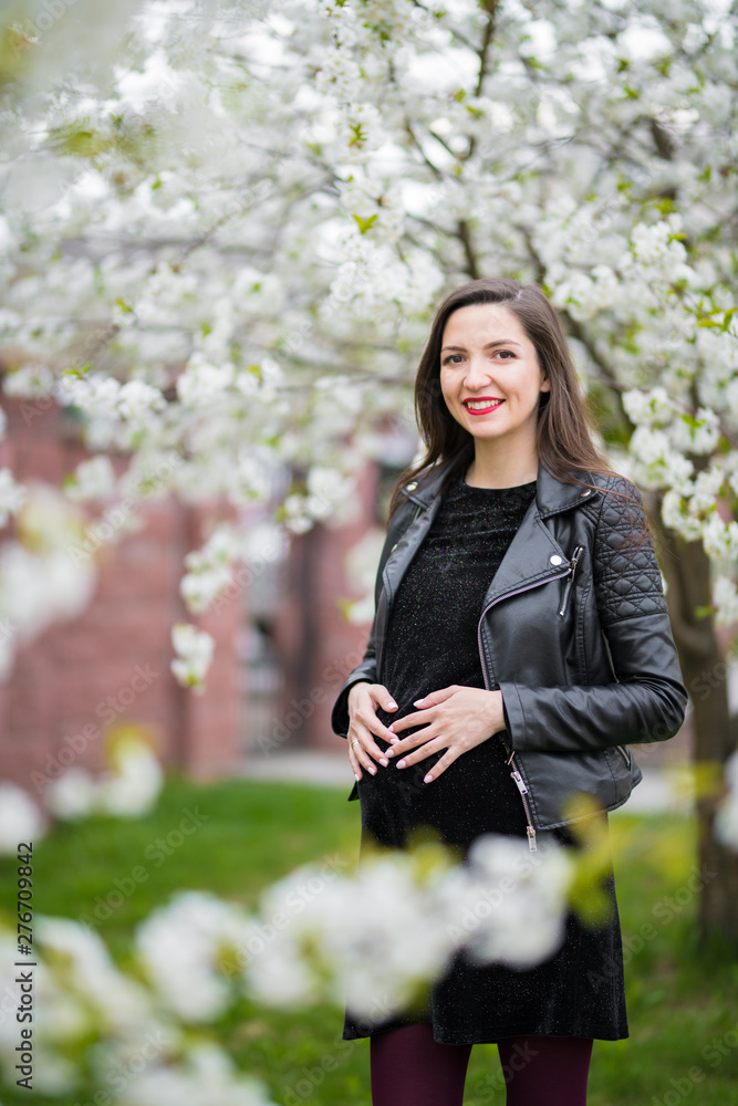 Pregnancy in the summer. Beautiful pregnant woman. Fashionable young parents, flowers and happiness of a young mother Pregnancy in the summer. Beautiful pregnant woman. Fashionable young parents, flowers and happiness of a young mother
