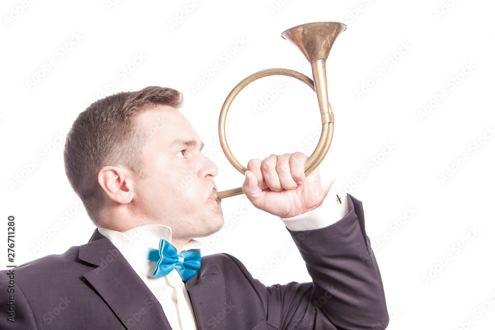 Funny man in blue bow tie blowing into the trumpet on white background in studio. Funny man in blue bow tie blowing into the trumpet on white background in studio.