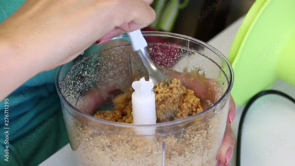 A woman checks the degree of grinding of almonds in the blender bowl. For the preparation of filling in glazed sweets. A woman checks the degree of grinding of almonds in the blender bowl. For the preparation of filling in glazed sweets.