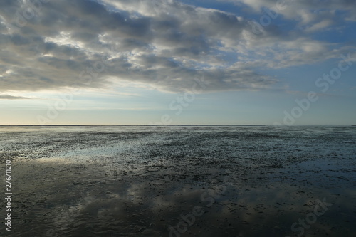 Early sunset on the North Sea directly on the beach. Orange Blue sky and low tide.