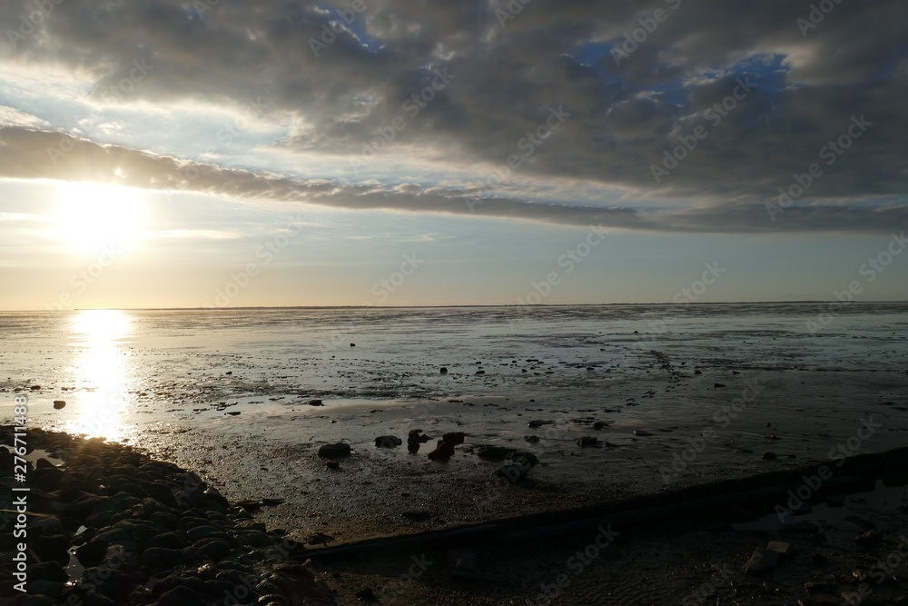 Obraz premium Early sunset on the North Sea directly on the beach. Orange/Blue sky and low tide.