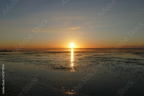Sunset on the North Sea directly on the beach. Orange sky and low tide.