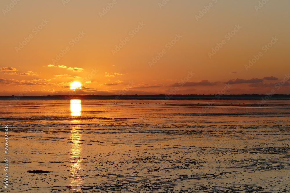 Sunset on the North Sea directly on the beach. Orange sky and low tide. Sunset on the North Sea directly on the beach. Orange sky and low tide.