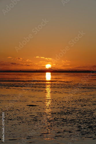 Sunset on the North Sea directly on the beach. Orange sky and low tide.