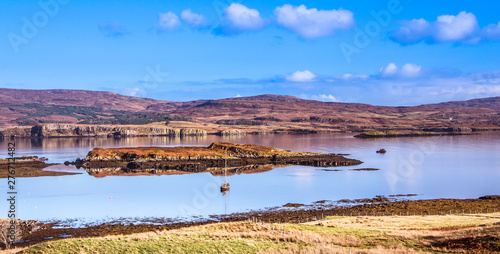 Isle of Skye Landscape - Yacht boat on Loch Dunvegan with mountains, heather covered hills and blue sky in the background © lukasz_kochanek