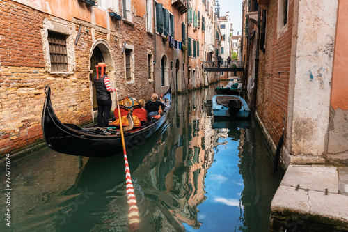 Venetian gondolier punts gondola through narrow canal waters of Venice, Italy © bortnikau