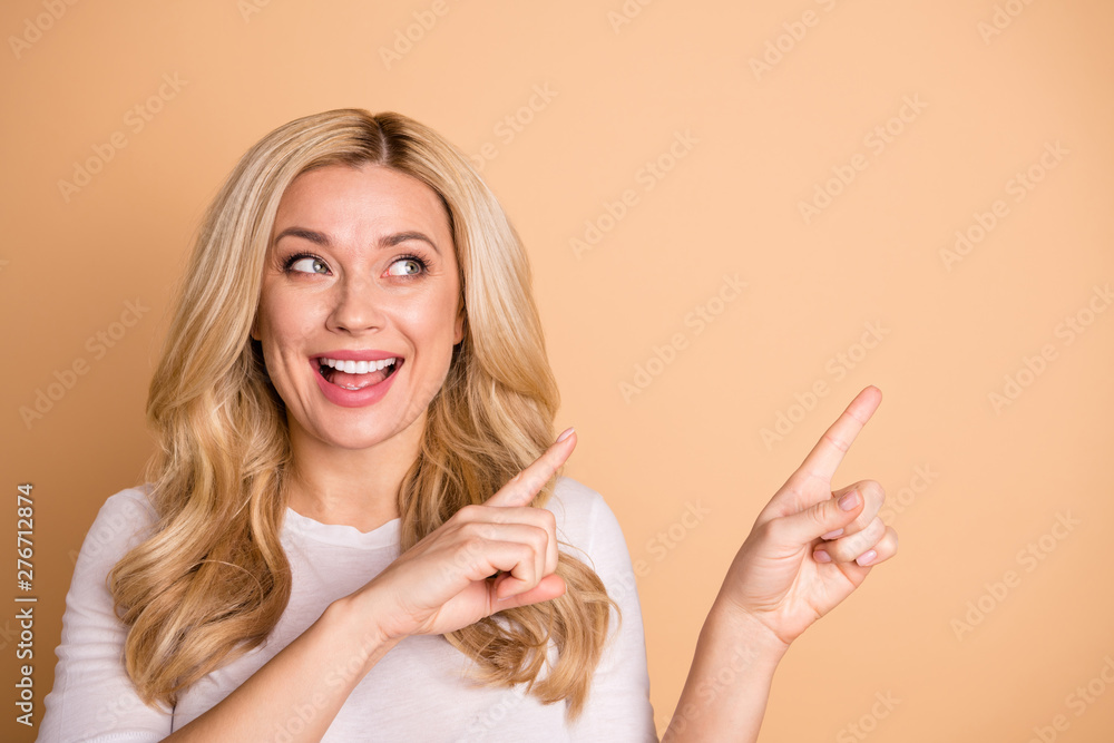 Close-up portrait of her she nice-looking lovely winsome attractive confident cheerful wavy-haired lady pointing two forefingers aside promotion sale discount isolated over beige pastel background - obrazy, fototapety, plakaty 