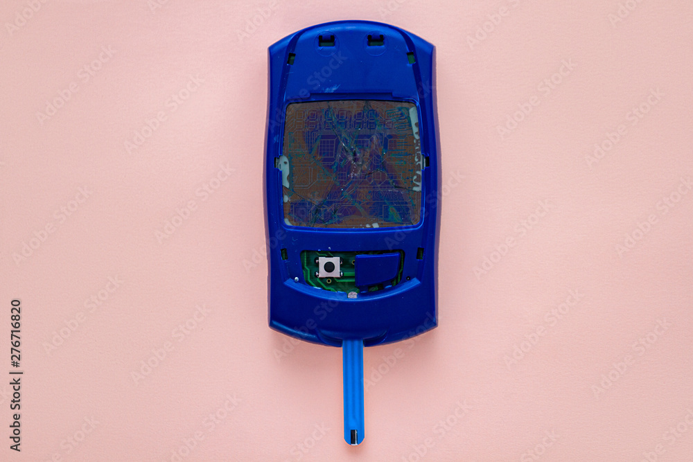Fototapeta premium Broken blood glucose meter on a pink background. Fight and control of diabetes.