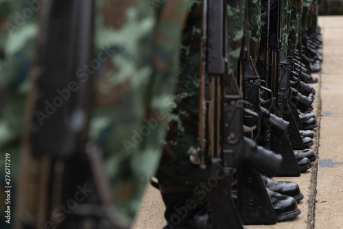 The Army soldiers stood in the same row carrying guns and wearing military uniforms.