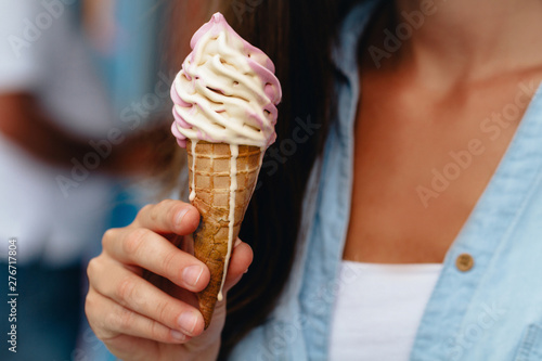 Young woman eating refreshing sweet ice cream cone in summer hot weather