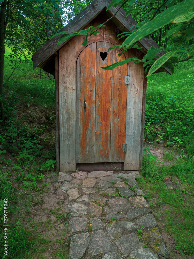 Wooden ecological composting toilet on countryside with a heart shape in the door