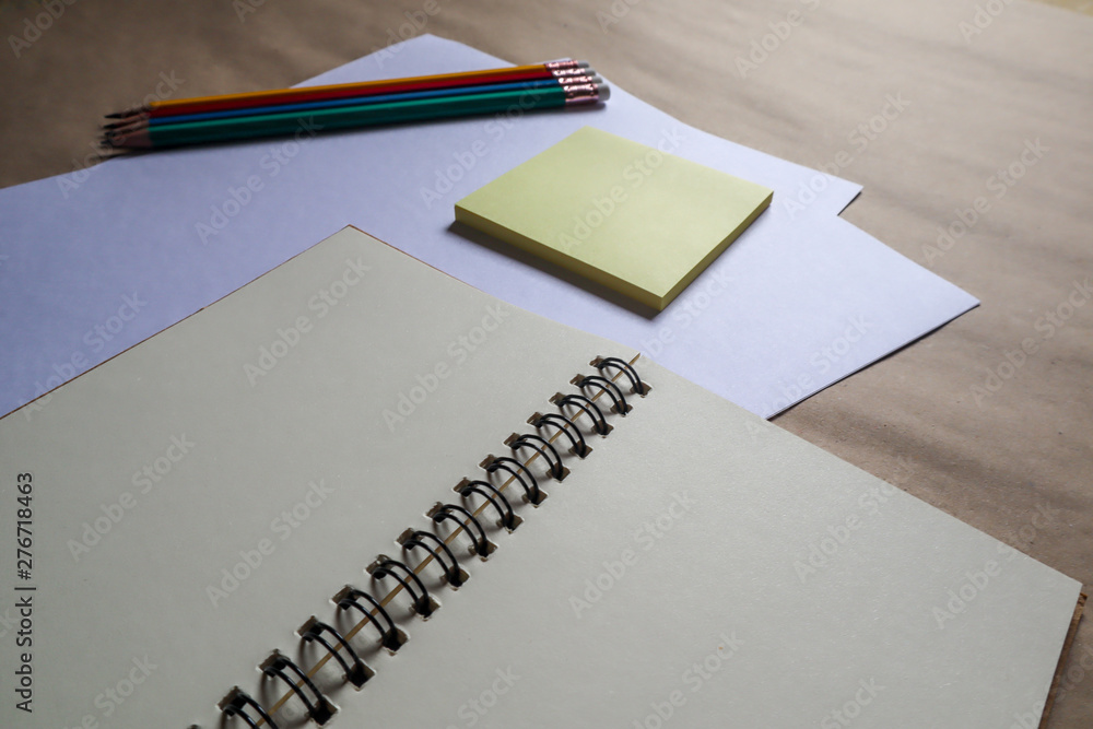 Multi-colored pencils and brown notebooks on a white background can be used to make backgrounds. Education, yellow note paper, education Multi-colored pencils and brown notebooks on a white background can be used to make backgrounds. Education, yellow note paper, education