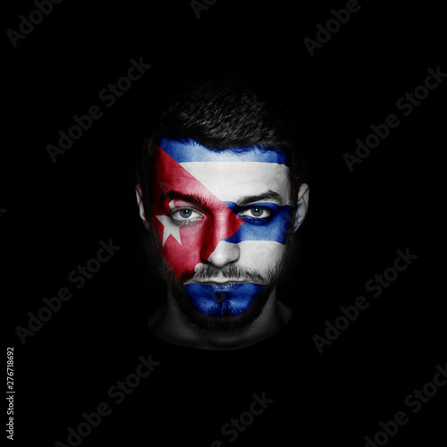 Flag of Cuba painted on a face of a man on black background.