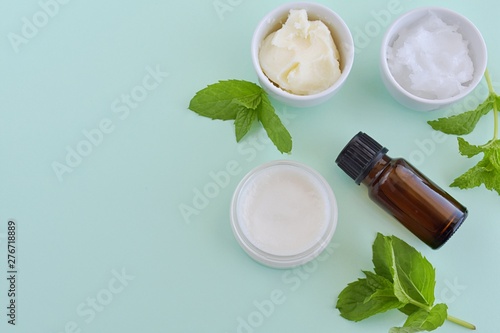 Natural homemade lip balm with shea butter, coconut oil and peppermint essential oil, top view on green background.