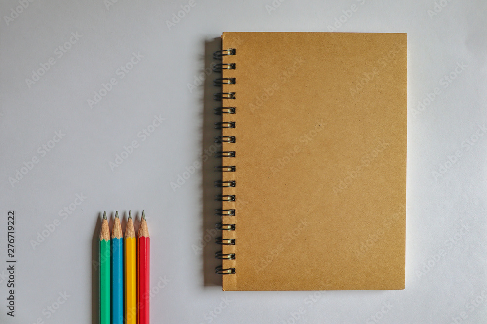 Multi-colored pencils and brown notebooks on a white background can be used to make backgrounds. Multi-colored pencils and brown notebooks on a white background can be used to make backgrounds.