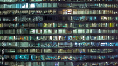 Billede på lærred Working evening in glass office building with numerous offices with glass walls