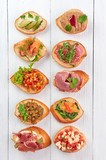 many different bruschettas at white wooden table top. italian cuisine appetizer with many ingridients