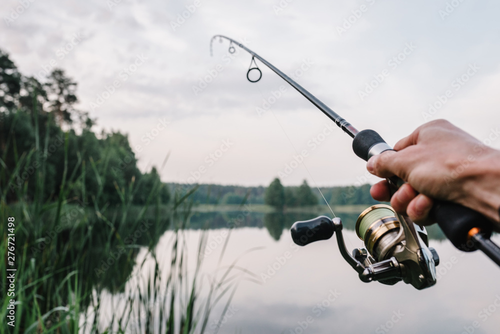 Fisherman With Rod Spinning Reel On The River Bank Fishing For