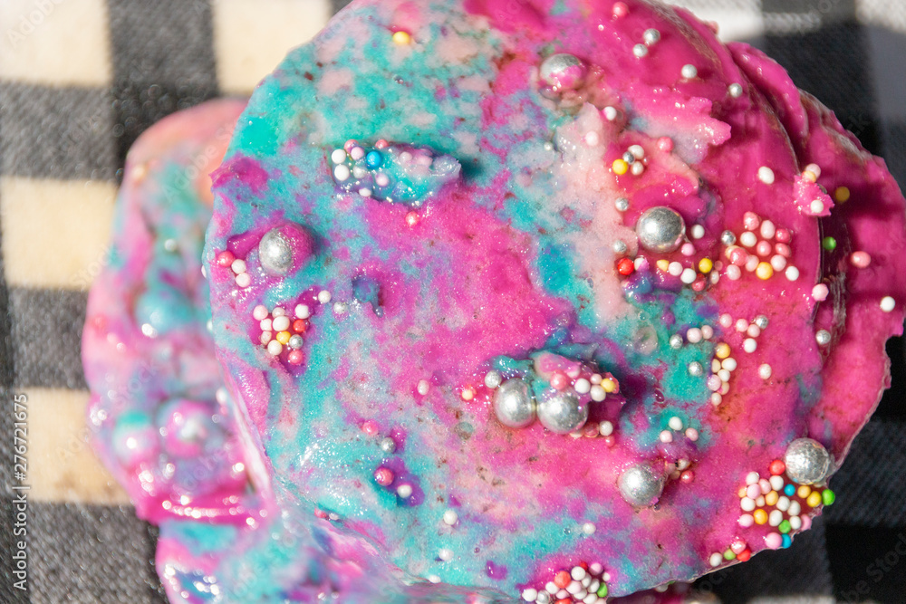 A close up view top of a melted multi colored cupcake with decor sitting in the warm sun