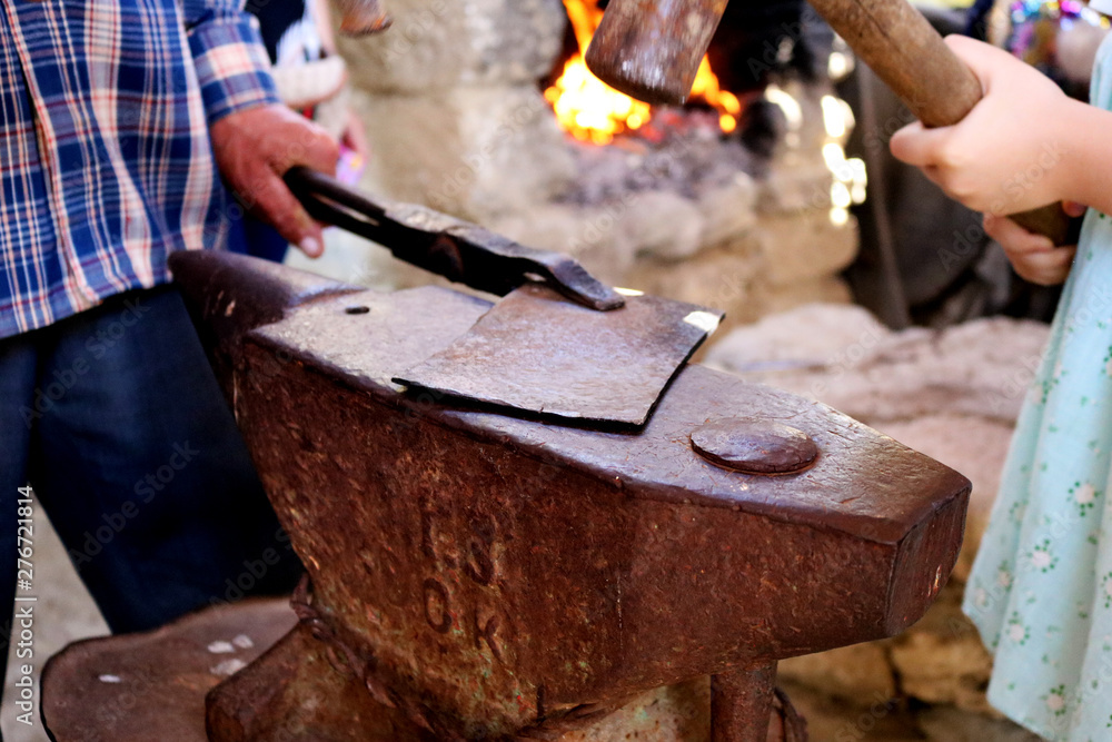 Smith teaches a child forges detail. Blacksmith craft. Smith teaches a child forges detail. Blacksmith craft.