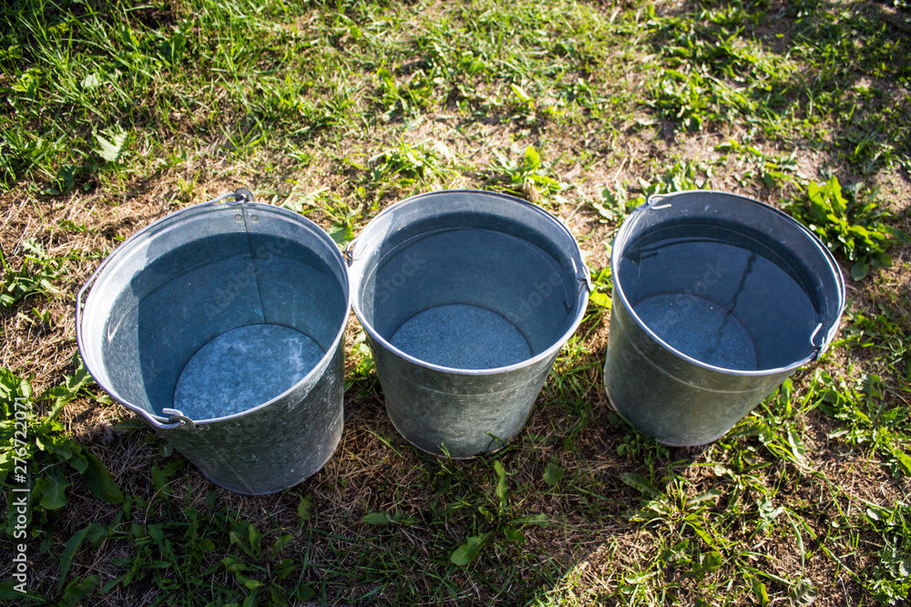 Three iron buckets of clean water on the grass Three iron buckets of clean water on the grass