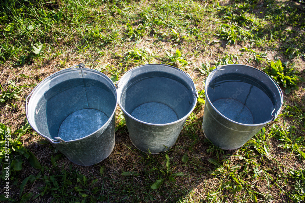 Three iron buckets of clean water on the grass Three iron buckets of clean water on the grass