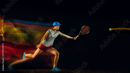 One caucasian woman playing tennis isolated on black background in mixed and stobe light. Fit young female player in motion or action during sport game. Concept of movement  sport  healthy lifestyle.