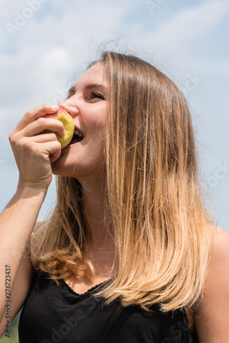 junge Frau mit langen haaren beißt herzhaft in einen Apfel