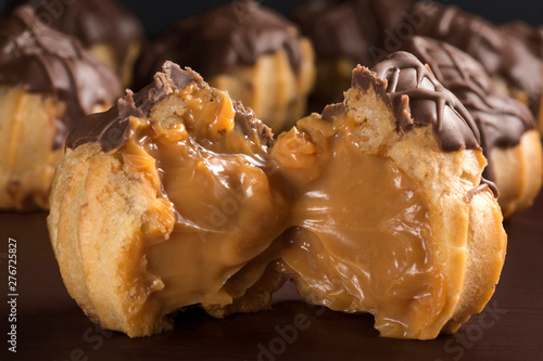One open  traditional type of Brazilian profiterolis bakery candy called carolina in wood background