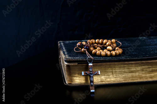 Rosary beads and prayer book on dark background. photo