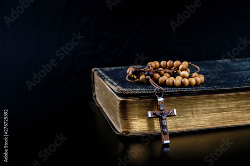 Rosary beads and prayer book on dark background. photo