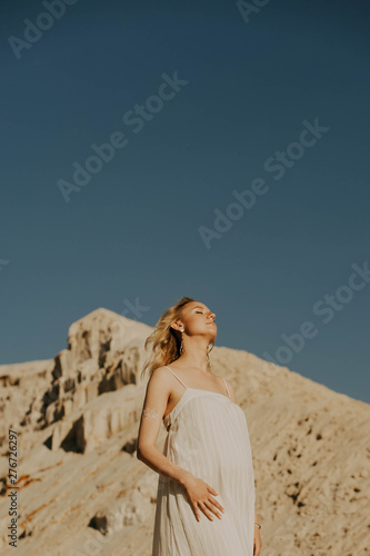 Portrait of pregnant woman on a desert background. © Julia