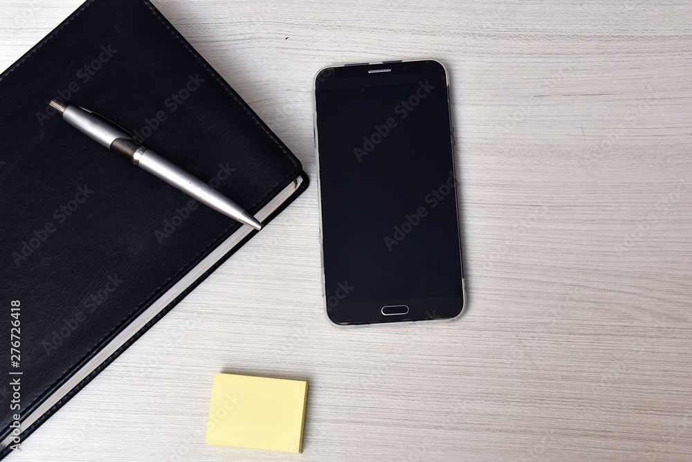 Phone book with pen on top and cellphone on the table Phone book with pen on top and cellphone on the table