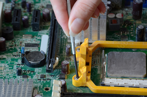 The process of fixing the green motherboard. Repairing an old chip on a computer against a dusty background. photo