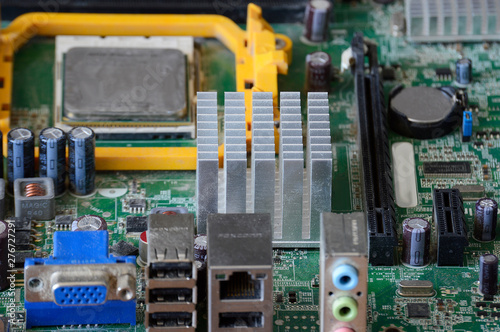 Background green and dusty motherboard close-up. Resistors, motherboard circuit connectors with a powerful processor chip photo