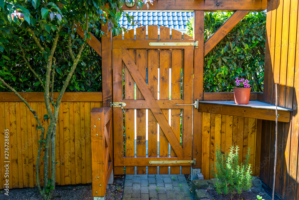 Wooden gate and fence on the back of the home garden. The gate is closed with a padlock.
