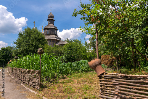 Typical Ukrainian landscape. Wooden old Church, wicker fence with pots. Ukraine. Sednev. photo