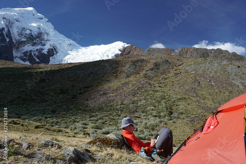 mountain climber sitting outside a tent and writing in his diary in the Cordillera Blanca in Peru