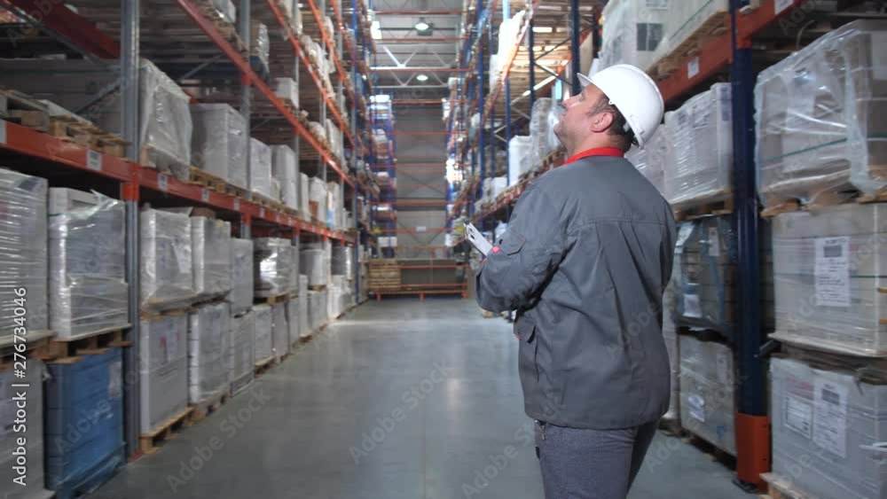 Warehouse worker goes back to the camera between the racks with the goods. 4K Slow Mo Warehouse worker goes back to the camera between the racks with the goods. 4K Slow Mo