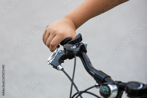 Close-up of a young boy’s hand holding steering wheel and brake of a bicycle. Shallow depth-of-field.